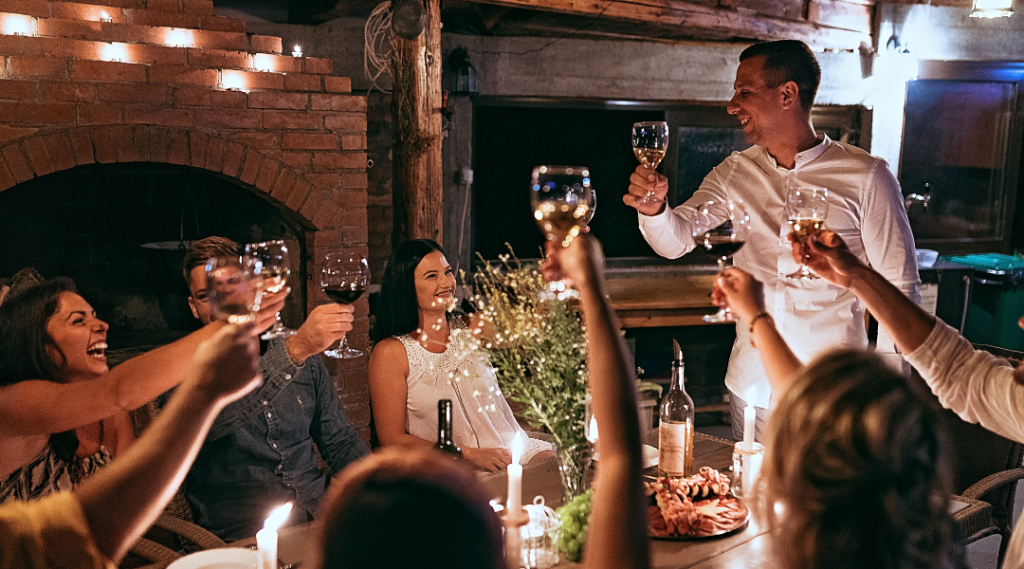 Friends gathered around an outdoor table at night, raising wine glasses to toast
